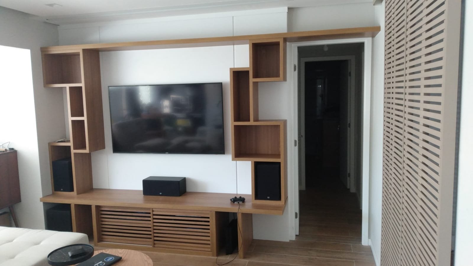 Painel de home theater integrado ao living, projeto da Prado Marcenaria
