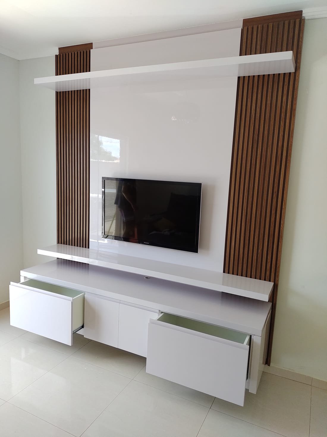 Painel de TV ripado em tom claro com bancada suspensa, projeto da Prado Marcenaria