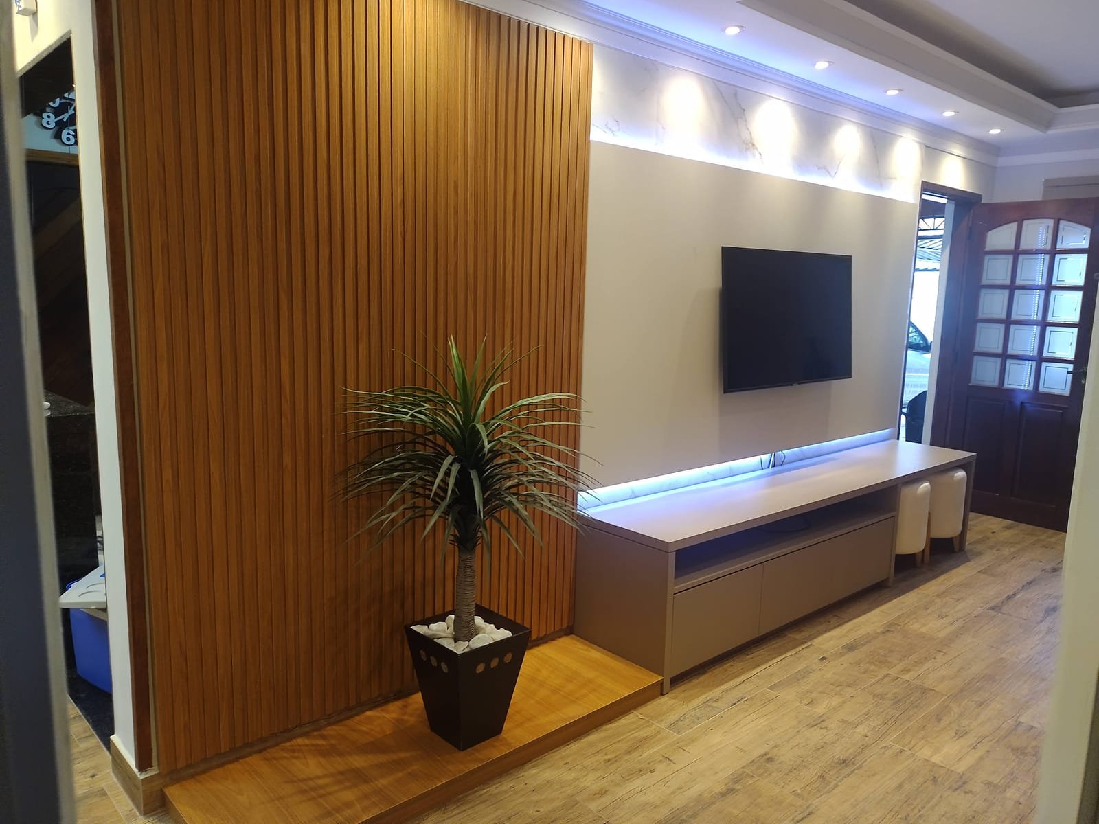 Sala de TV com revestimento ripado em madeira e rack suspenso, projeto da Prado Marcenaria